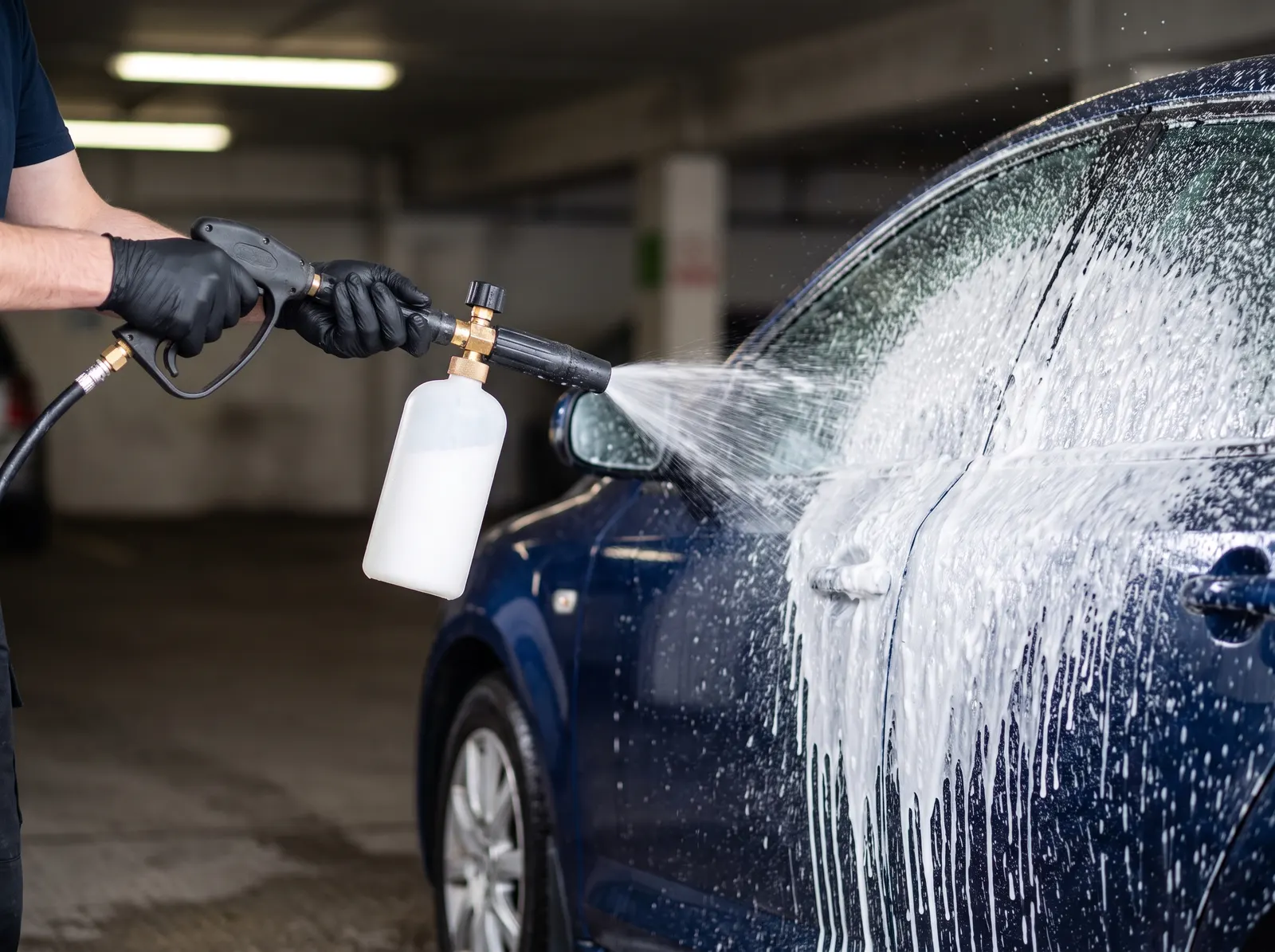 Foam cannon covering a car in a thick layer of white snow foam